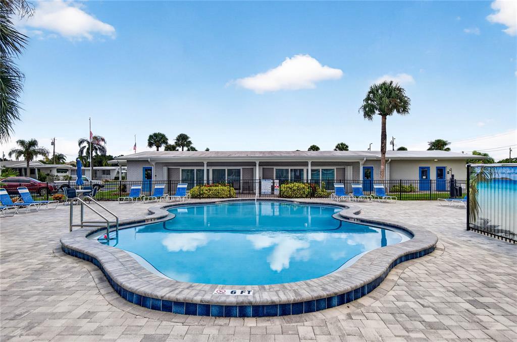 A swimming pool with a stone deck sits in front of a single-story building — 2000 E BAY DRIVE UNIT 33, LARGO, FL