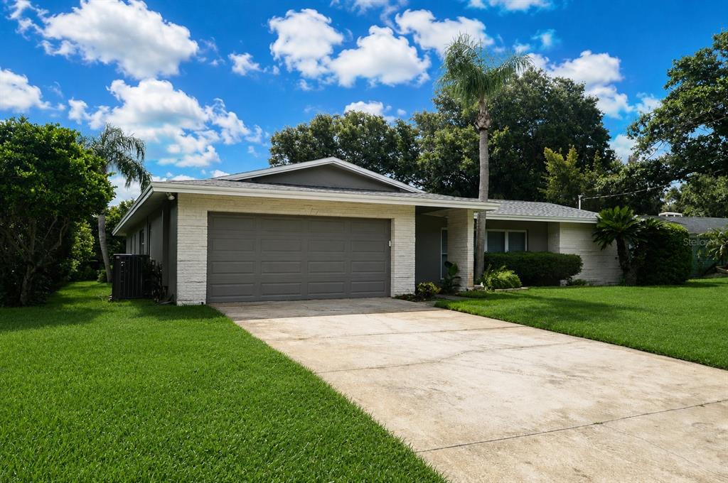 A single-story house with a gray garage door, white brick accents, and a concrete driveway — 981 DAMROSCH STREET, LARGO, FL