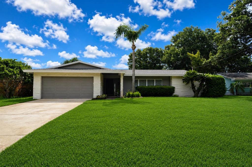 A single-story house with a gray garage, white brick accents, and a large front lawn — 981 DAMROSCH STREET, LARGO, FL