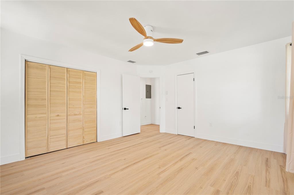 A bedroom with light wood flooring, a ceiling fan, and louvered closet doors — 2002 VIRGINIA DRIVE, BRADENTON, FL