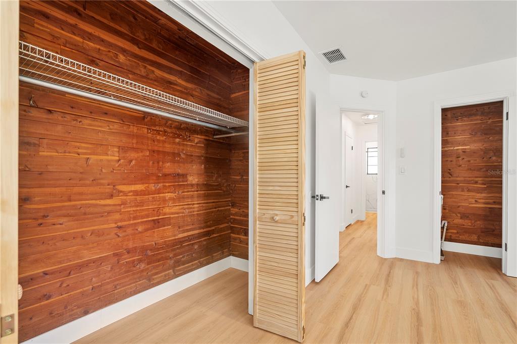 A room features light wood flooring, white walls, and closets lined with horizontal wood planks — 2002 VIRGINIA DRIVE, BRADENTON, FL