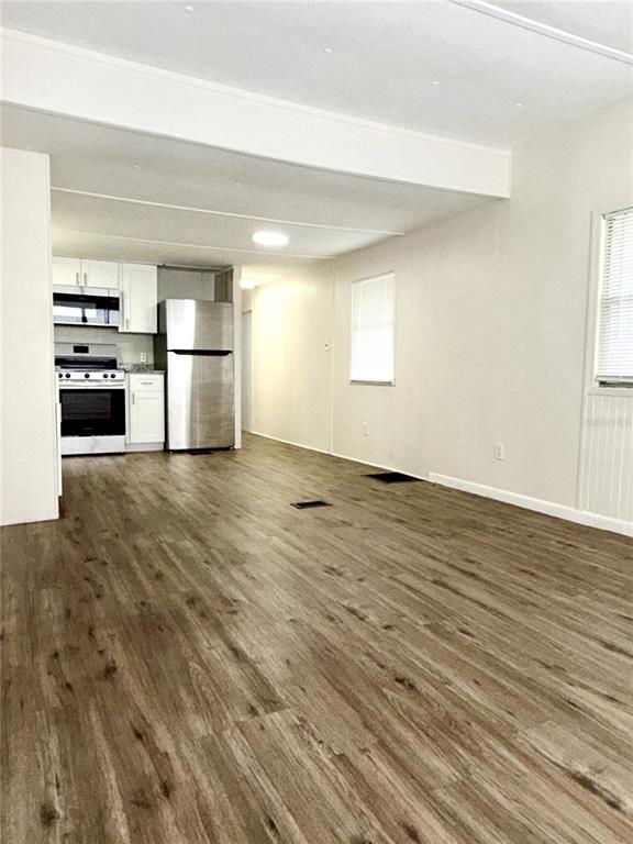A kitchen with stainless steel appliances and white cabinets opens into a living area — 7134 LOFTY DRIVE, PORT RICHEY, FL