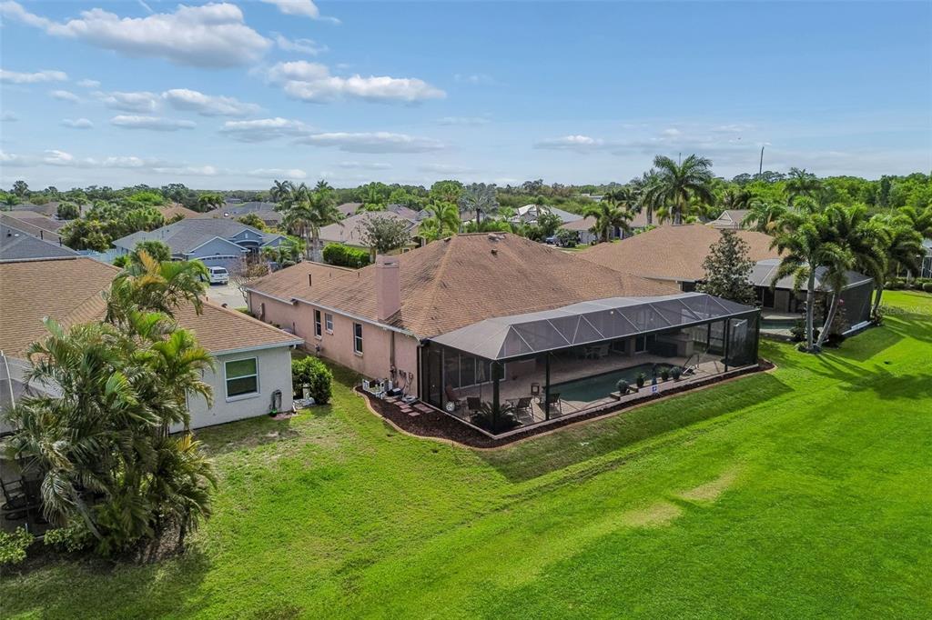 An aerial view of a suburban house with a screened-in pool and a large lawn — 566 PLANTERS MANOR WAY, BRADENTON, FL