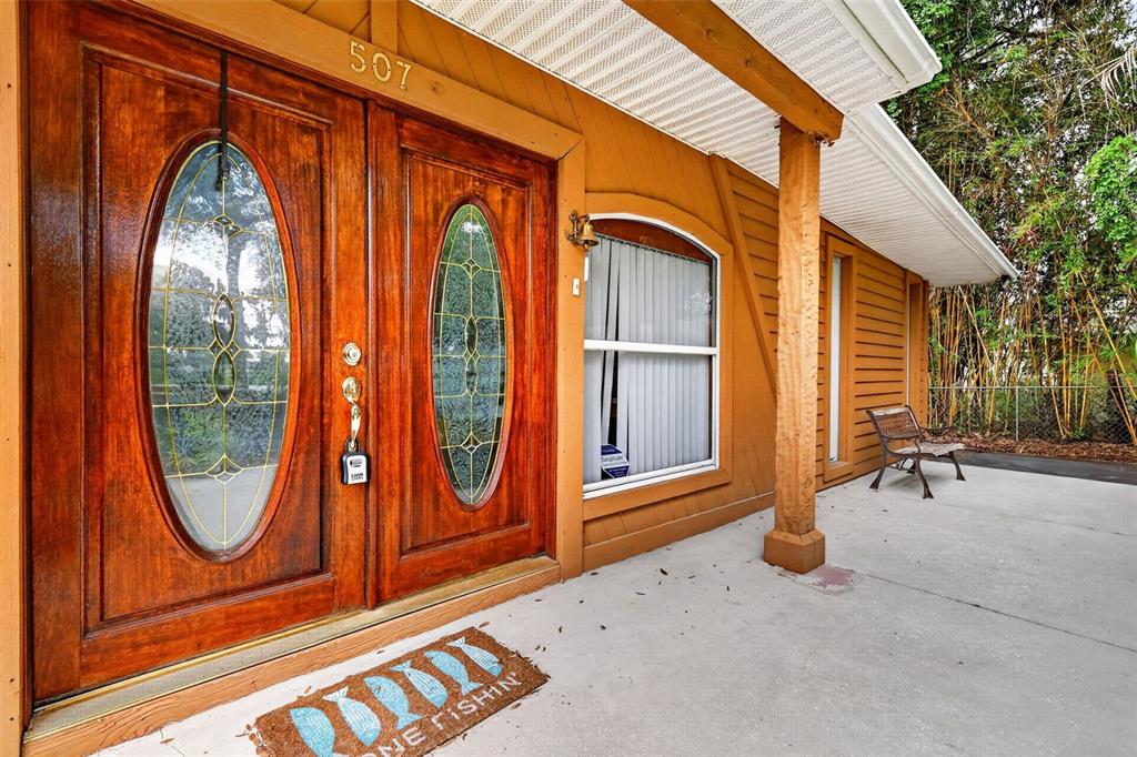 A wooden front porch features double doors with oval glass inserts and a concrete floor — 507 LAKESHORE DRIVE, EUSTIS, FL