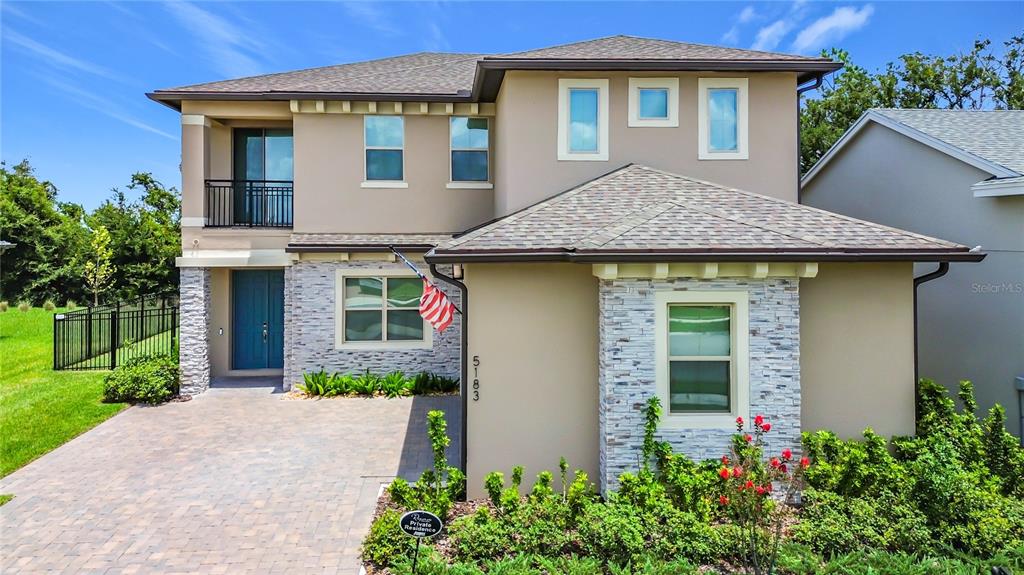 A two-story suburban house features a stone-accented facade, a paved driveway, and a balcony — 5183 BUTTONSAGE DRIVE, ST CLOUD, FL