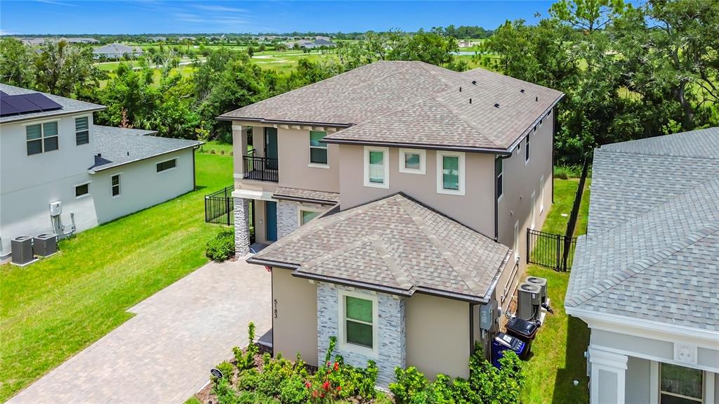 An aerial view shows the exterior of a two-story suburban house with a paved driveway — 5183 BUTTONSAGE DRIVE, ST CLOUD, FL