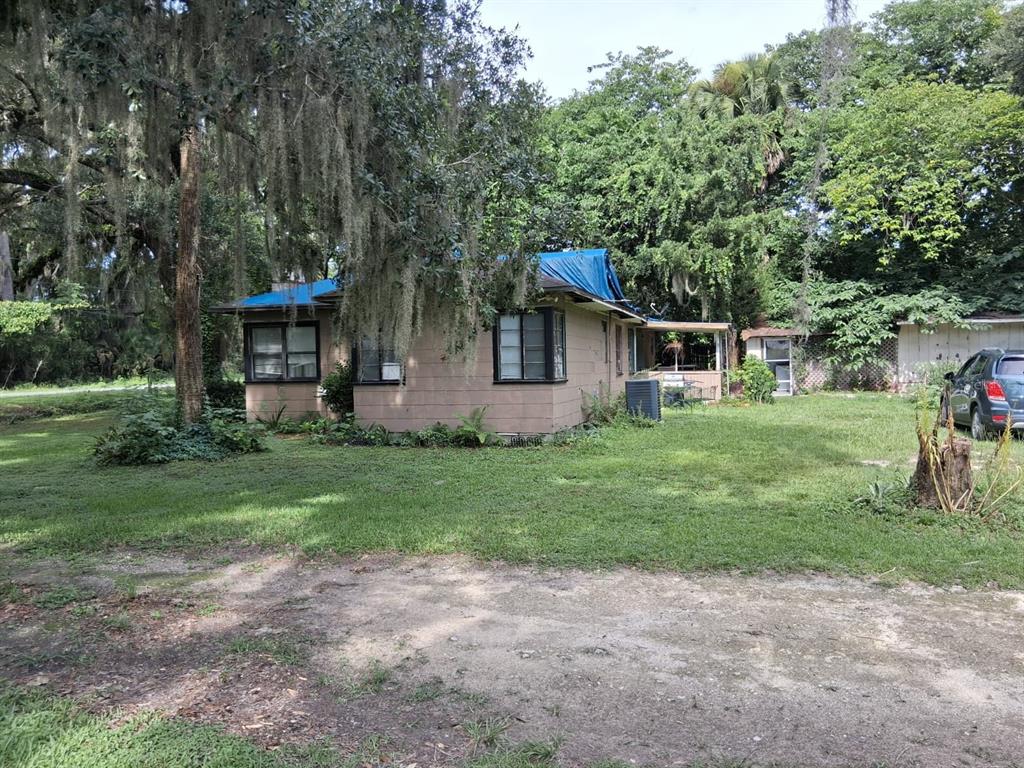A single-story house with a blue tarp on the roof sits on a grassy lot — 5741 NW 191ST PLACE, REDDICK, FL