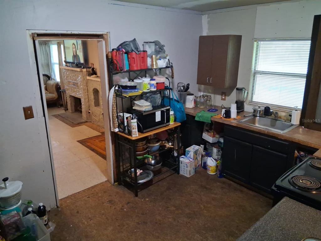 A kitchen features dark cabinets, a metal shelving unit, and a doorway to a living area — 5741 NW 191ST PLACE, REDDICK, FL
