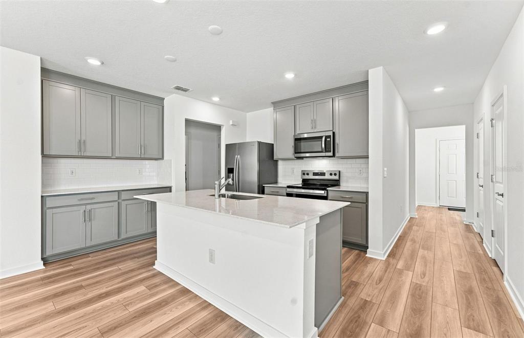 A dining area with a round table and chairs sits adjacent to a modern kitchen — 7923 PALM PARADISE PLACE, PARRISH, FL