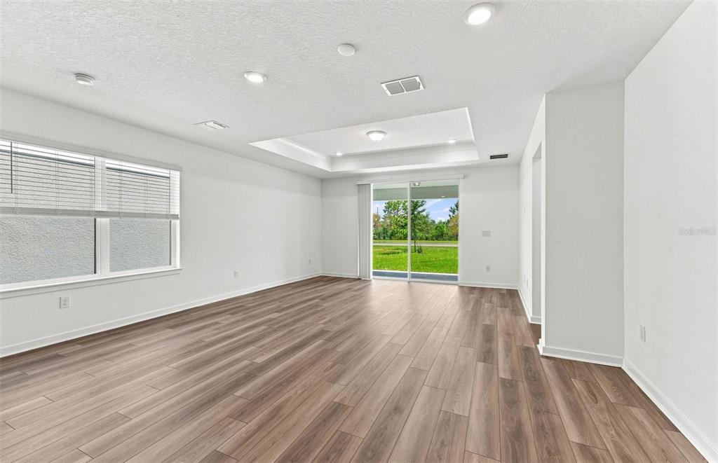An open-concept living and dining area features a slatted accent wall and neutral furniture — 7923 PALM PARADISE PLACE, PARRISH, FL