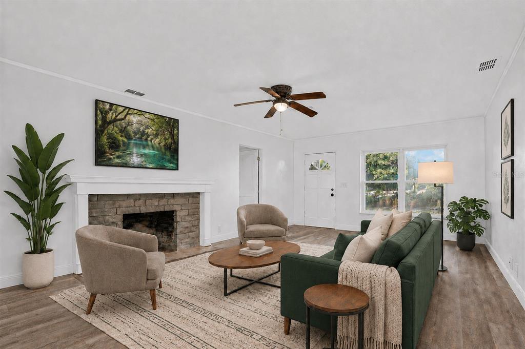 A living room features a stone fireplace, green sofa, two armchairs, and wood-look flooring — 1202 ORANOLE ROAD, MAITLAND, FL