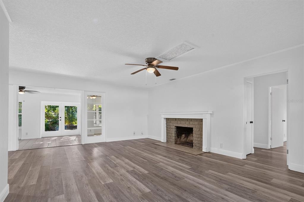A living room with wood-look flooring, a brick fireplace, and a ceiling fan — 1202 ORANOLE ROAD, MAITLAND, FL