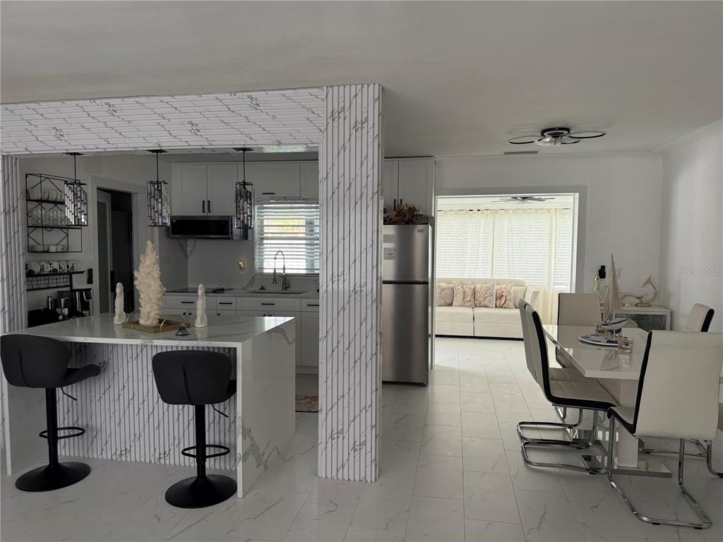 A kitchen with a marble-topped island and stools opens into a dining and living area — 59 45TH AVENUE, ST PETE BEACH, FL