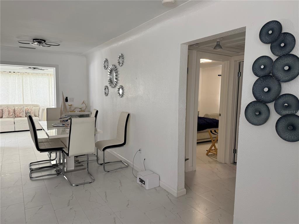 A dining area with a white table and chairs sits adjacent to a bedroom doorway — 59 45TH AVENUE, ST PETE BEACH, FL
