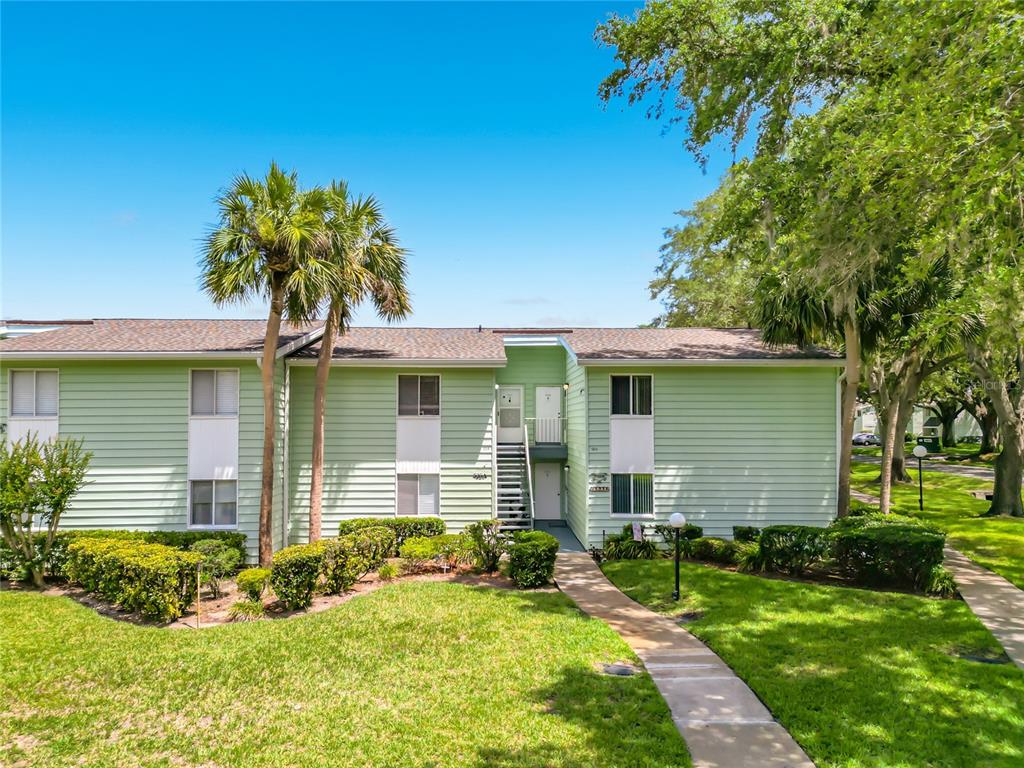 A two-story light green apartment building with a central staircase and surrounding landscaping — 533 MIDWAY DRIVE UNIT B, OCALA, FL