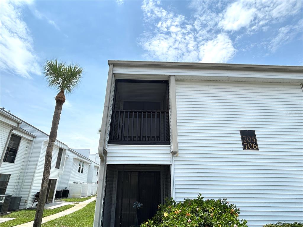 An outdoor staircase leads to a dark entryway between two white vinyl-sided building walls — 705 HAVEN PLACE UNIT 705, TARPON SPRINGS, FL
