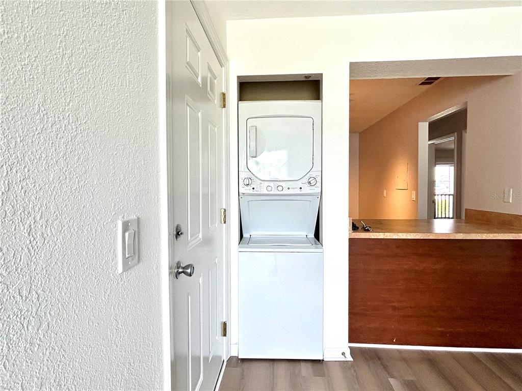 An interior view shows a living area with wood-look flooring, a ceiling fan, and kitchen — 705 HAVEN PLACE UNIT 705, TARPON SPRINGS, FL
