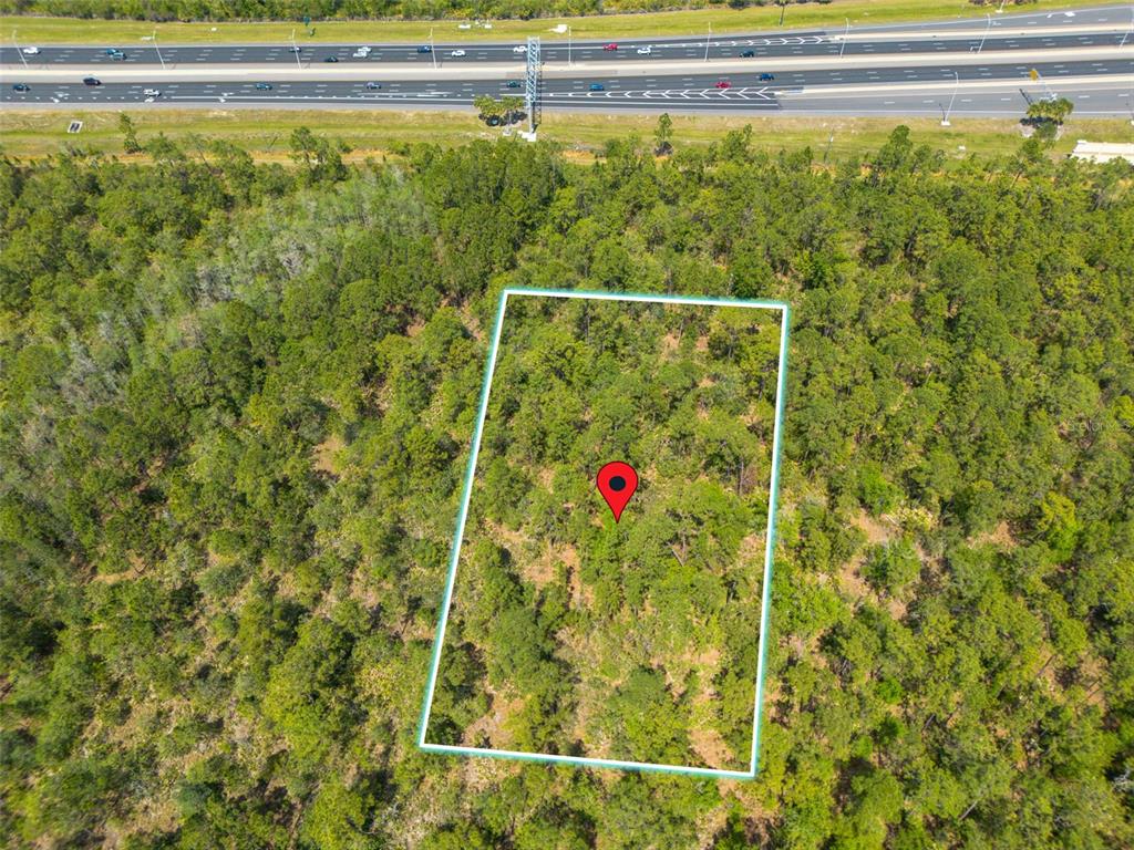 An aerial view shows a rectangular plot of land outlined in blue near a highway — SR-535, ORLANDO, FL