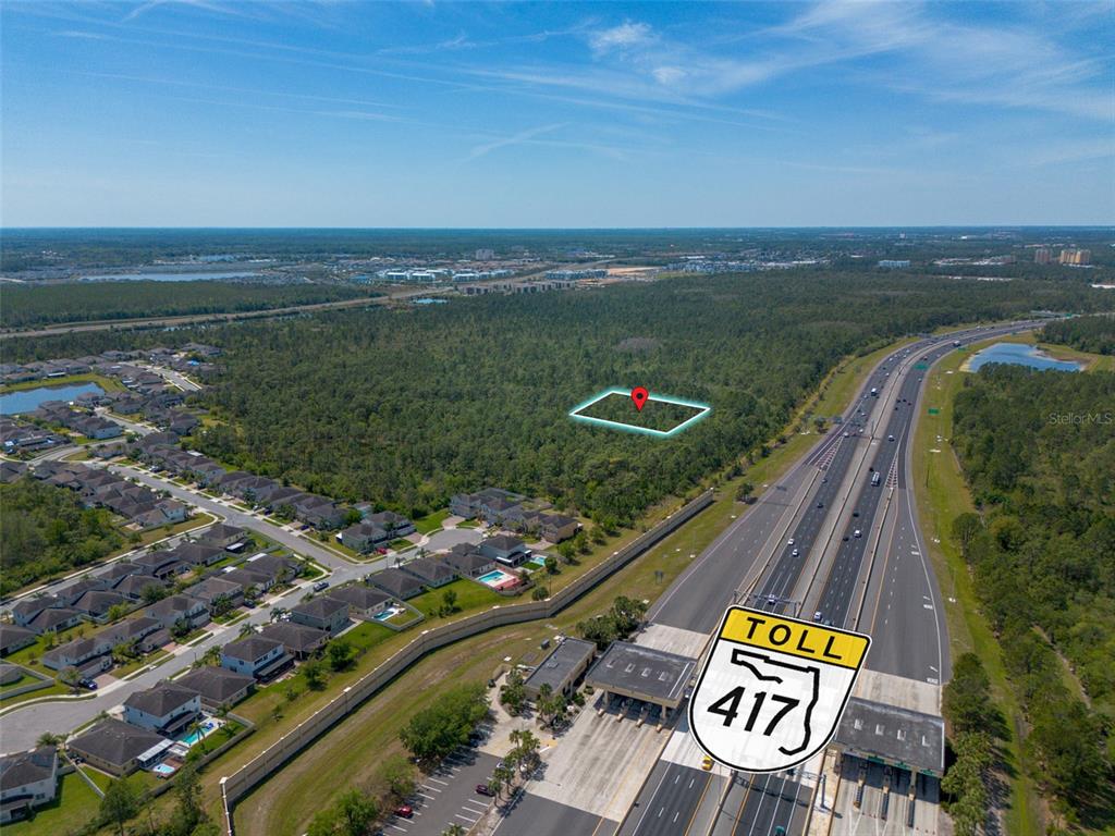 An aerial view shows a vacant, wooded lot highlighted by a red pin near a highway — SR-535, ORLANDO, FL