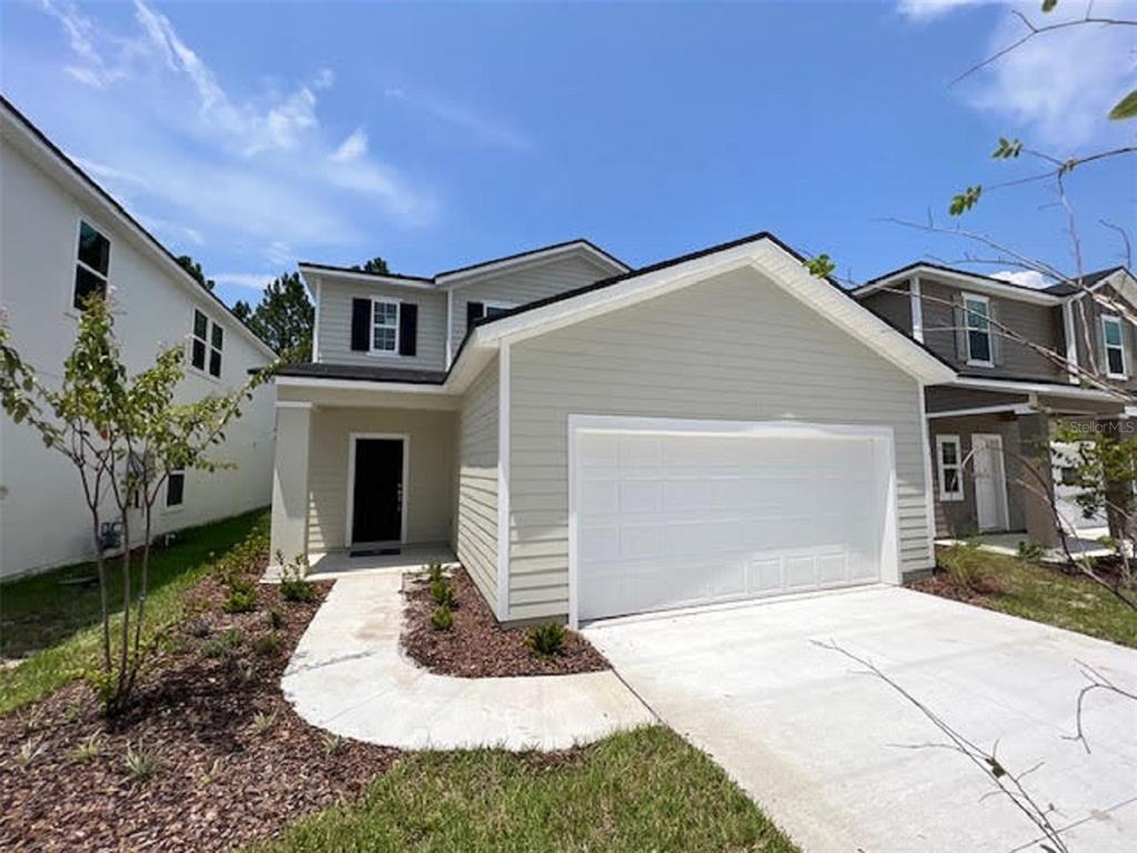 A two-story house with light-colored siding, a white garage door, and a front walkway — 14371 EPPLY DRIVE, JACKSONVILLE, FL