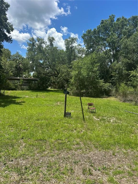 A grassy lot features a small, weathered structure, a folding chair, and a private property sign — 10828 E FREDDY STREET, INVERNESS, FL