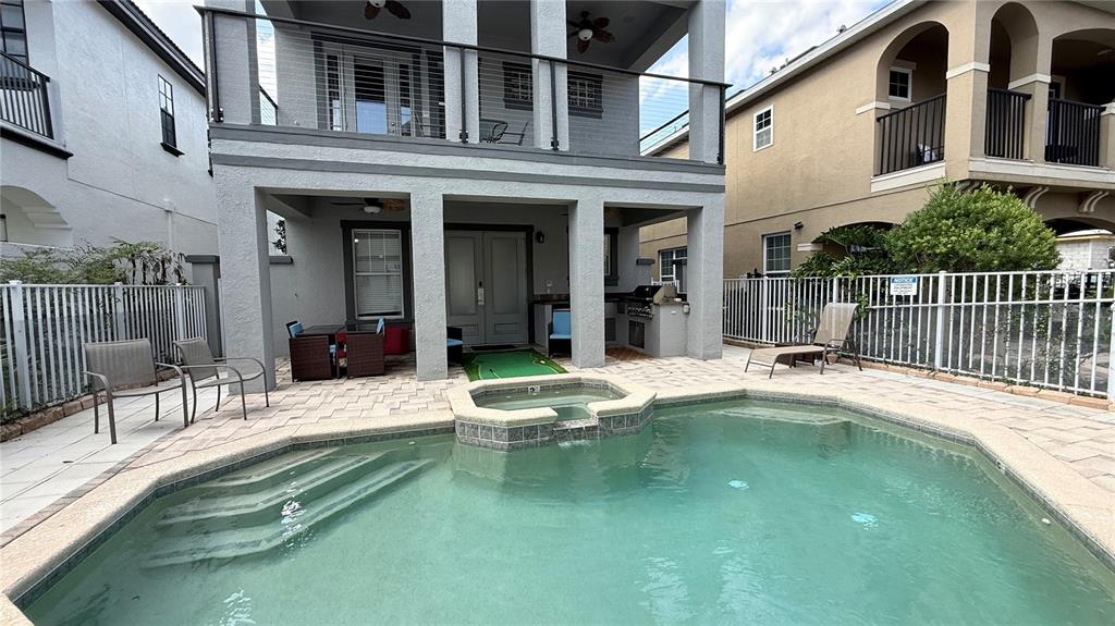 A two-story house features a backyard patio with a pool, spa, and outdoor seating area — 7810 WHITEMARSH WAY, REUNION, FL