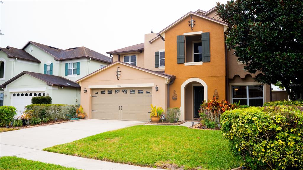 A two-story house with a tan stucco exterior, a two-car garage, and a landscaped front yard — 2804 POLSON DRIVE, KISSIMMEE, FL