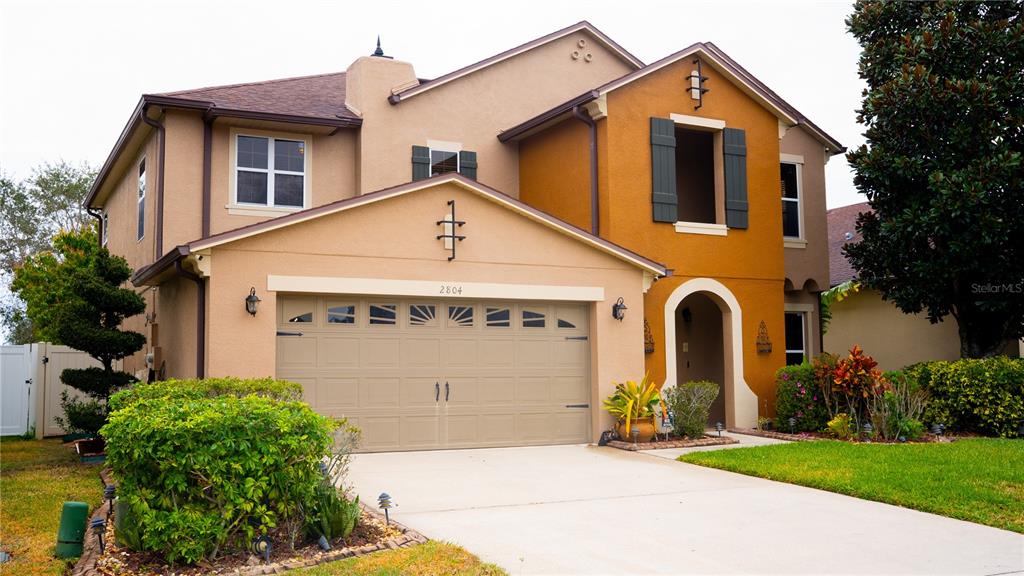 A two-story house with a tan stucco exterior, a two-car garage, and an arched entryway — 2804 POLSON DRIVE, KISSIMMEE, FL
