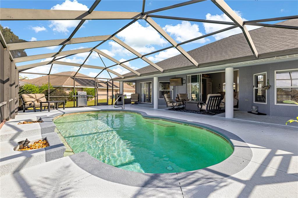 A screened-in patio features a swimming pool, outdoor seating, and a covered porch area — 5430 COUNTY ROAD 125, WILDWOOD, FL