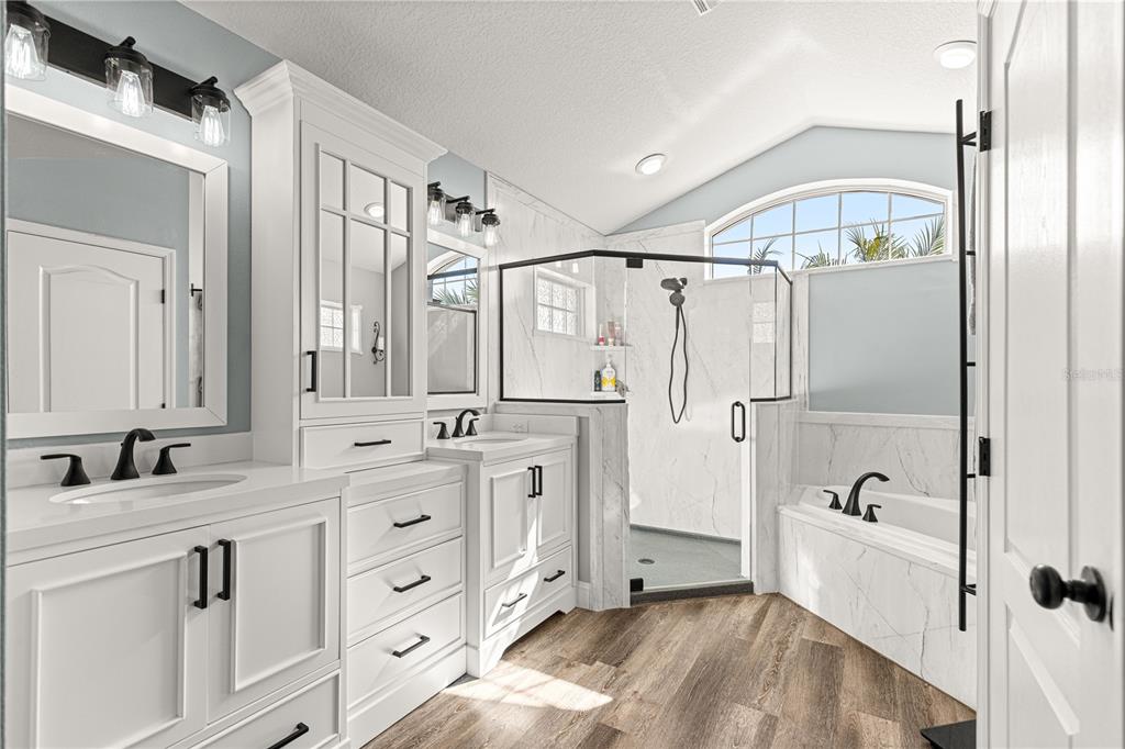 A modern bathroom features dual white vanities, a glass-enclosed shower, and a soaking tub — 5430 COUNTY ROAD 125, WILDWOOD, FL