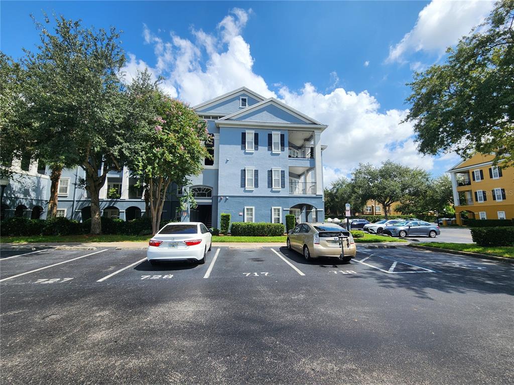 A blue three-story apartment building stands behind a parking lot with two parked cars — 3621 CONROY ROAD UNIT 726, ORLANDO, FL