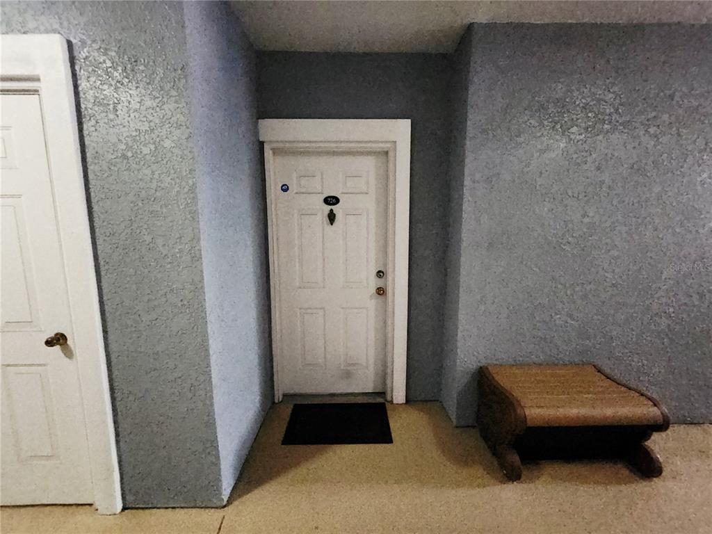 A white door labeled 726 sits between a smaller door and a small wooden bench — 3621 CONROY ROAD UNIT 726, ORLANDO, FL