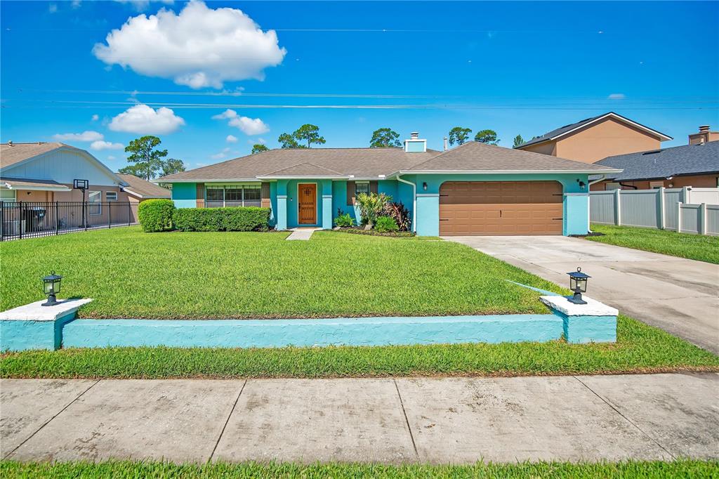 A single-story house with turquoise stucco walls, a brown garage door, and a front lawn — 4520 BRIDGEWATER DRIVE, ORLANDO, FL