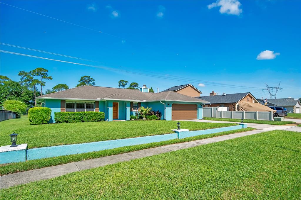 A single-story turquoise house with a two-car garage and a low retaining wall — 4520 BRIDGEWATER DRIVE, ORLANDO, FL