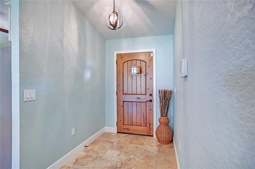 An entryway features light blue walls, tile flooring, a wooden door, and a globe pendant light — 4520 BRIDGEWATER DRIVE, ORLANDO, FL