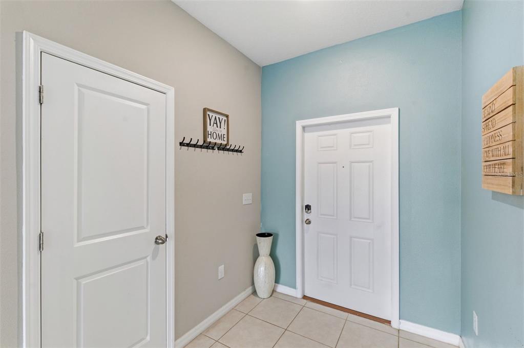 An entryway features a white front door, a coat rack, and a tall decorative vase — 8606 REEDVILLE STREET, NEW PORT RICHEY, FL