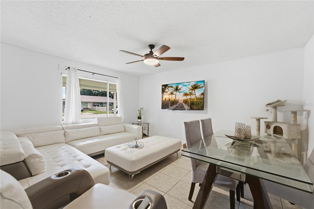 A living and dining room with white tile floors, a white sectional, and glass table — 524 PIGEON CIR, ORLANDO, FL