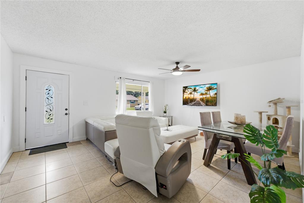 A living and dining area with white tile floors, a white sectional, and a glass table — 524 PIGEON CIR, ORLANDO, FL