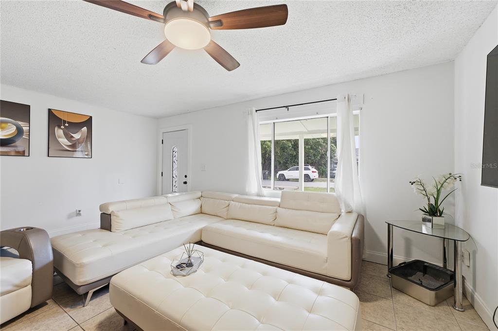 A living room features a white sectional sofa, a matching ottoman, and a ceiling fan — 524 PIGEON CIR, ORLANDO, FL