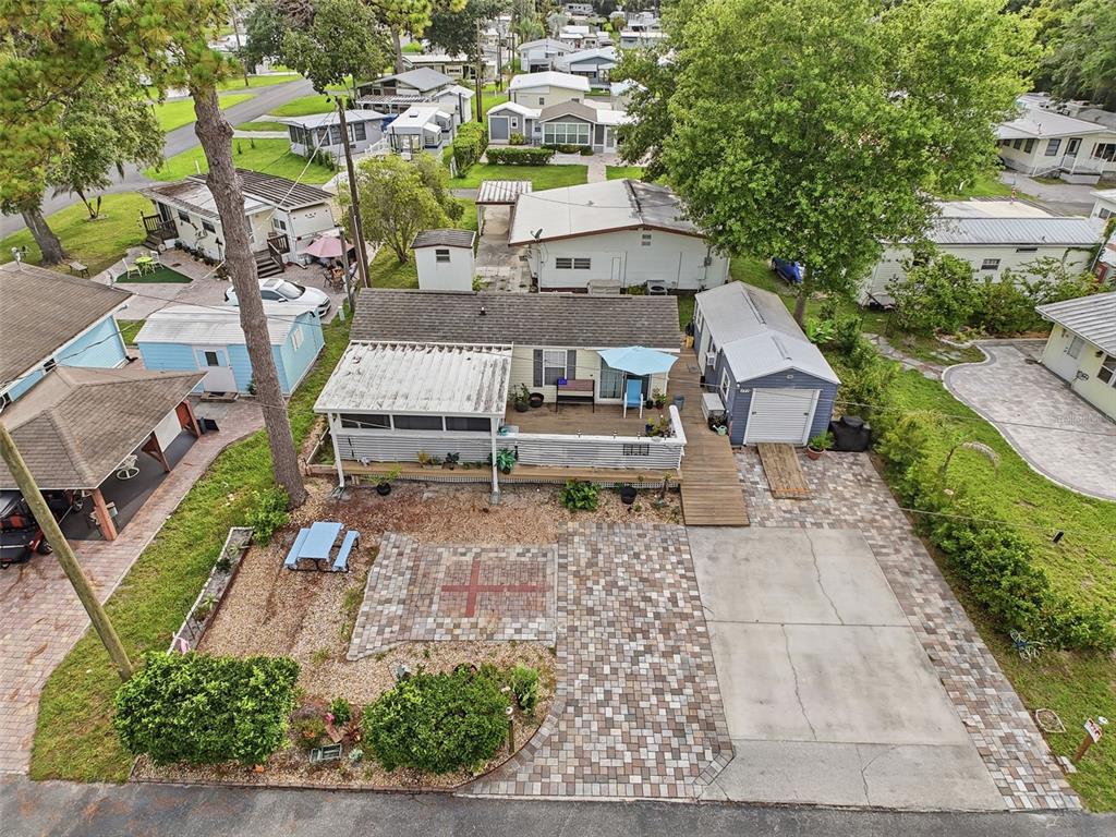 A yellow mobile home features a screened porch, a paver patio, and a detached storage shed — 2092 CULBREATH ROAD UNIT A42, BROOKSVILLE, FL