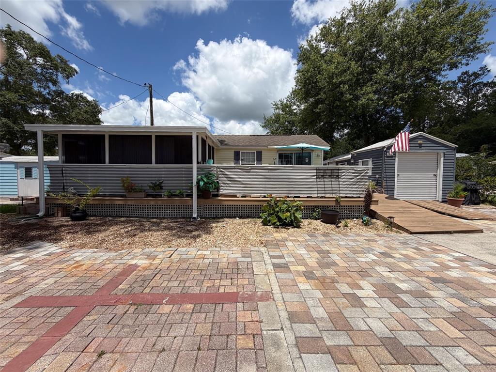 A manufactured home features a large screened porch, a wooden deck, and an adjacent shed — 2092 CULBREATH ROAD UNIT A42, BROOKSVILLE, FL