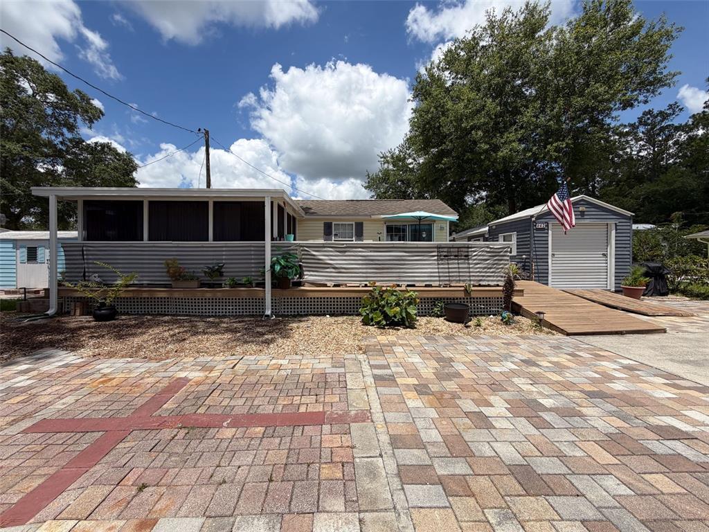 A house with a wooden ramp, a screened porch, and a shed with a roll-up door — 2092 CULBREATH ROAD UNIT A42, BROOKSVILLE, FL