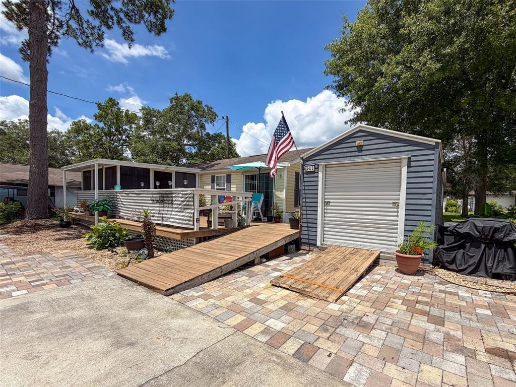 A single-story house with a screened porch, paver patio, and detached shed in a yard — 2092 CULBREATH ROAD UNIT A42, BROOKSVILLE, FL