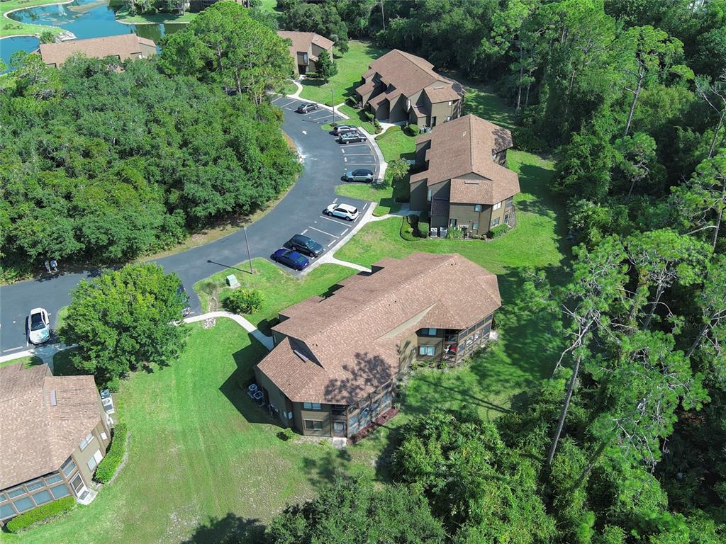 An aerial view shows several multi-story apartment buildings surrounded by trees, lawns, and parking lots — 5 SHERBURY COURT, PALM COAST, FL