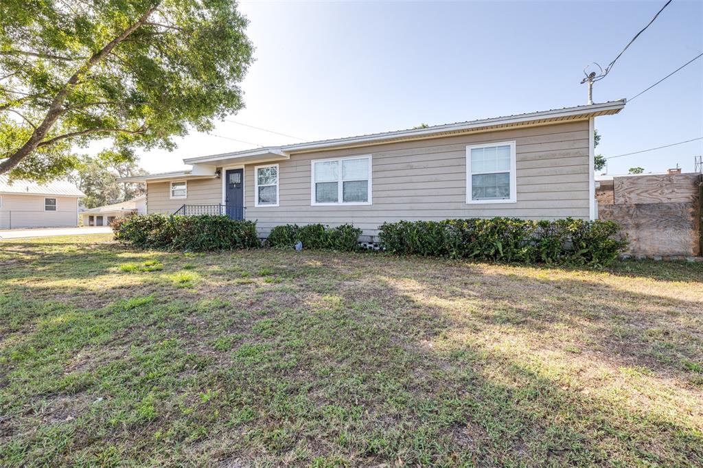 A single-story house with tan horizontal siding, a dark front door, and a grassy yard — 3935 CLUBHOUSE ROAD, HIGHLAND CITY, FL