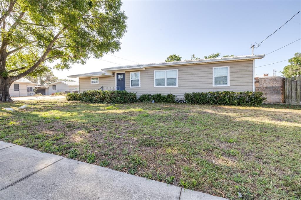 A single-story house with tan horizontal siding and a dark blue front door — 3935 CLUBHOUSE ROAD, HIGHLAND CITY, FL