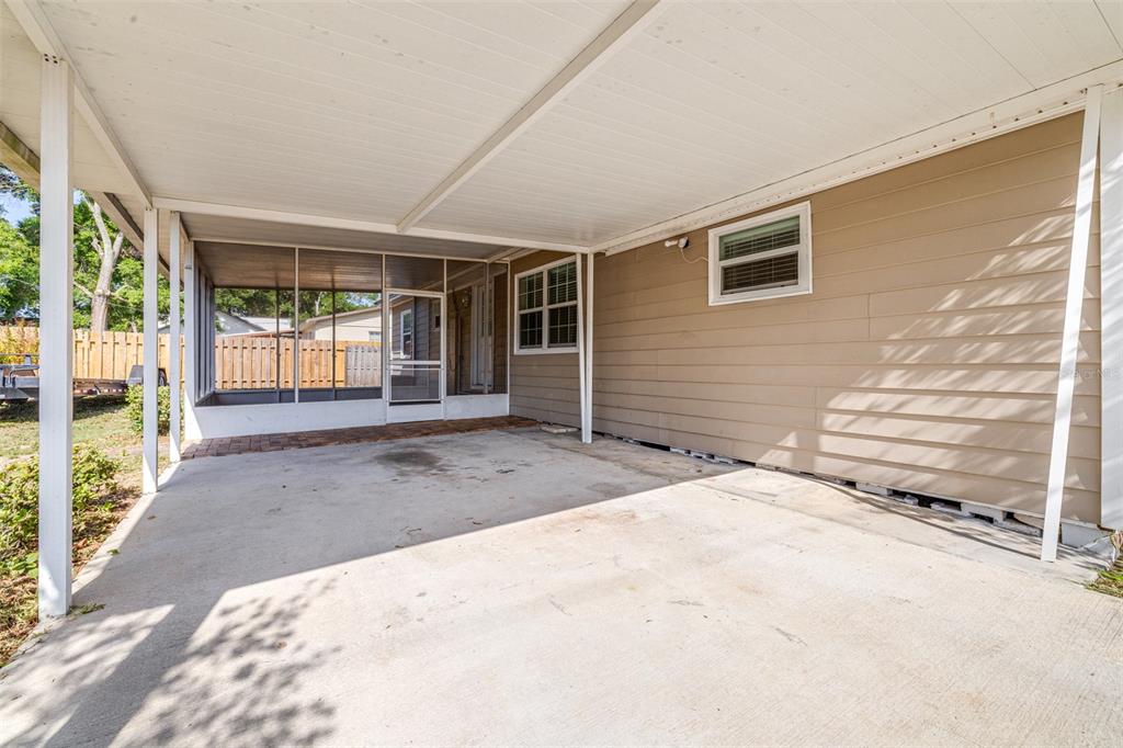A concrete carport with a screened-in porch area attached to the side of a house — 3935 CLUBHOUSE ROAD, HIGHLAND CITY, FL