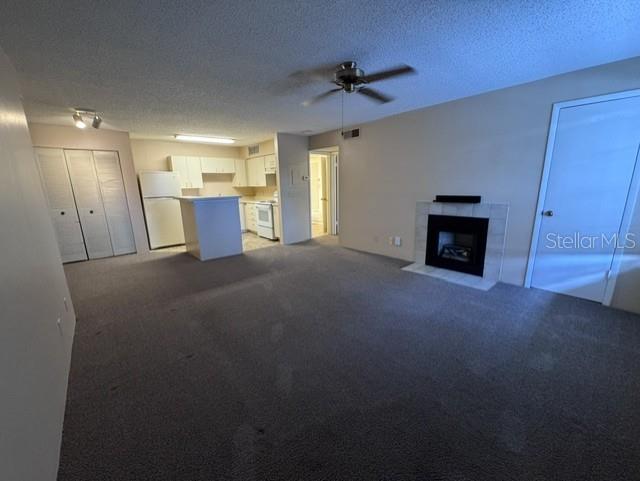 An open-concept living room features a fireplace, carpeted flooring, and an adjacent kitchen area — 320 FORESTWAY CIRCLE UNIT 203, ALTAMONTE SPRINGS, FL
