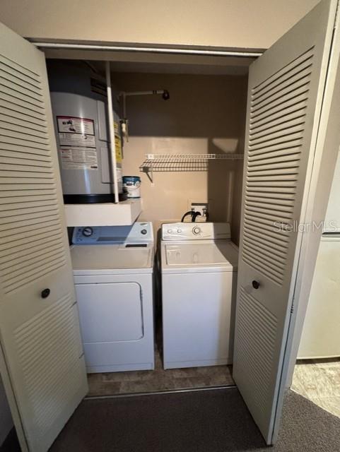 A closet contains a water heater above a white washer and dryer set — 320 FORESTWAY CIRCLE UNIT 203, ALTAMONTE SPRINGS, FL