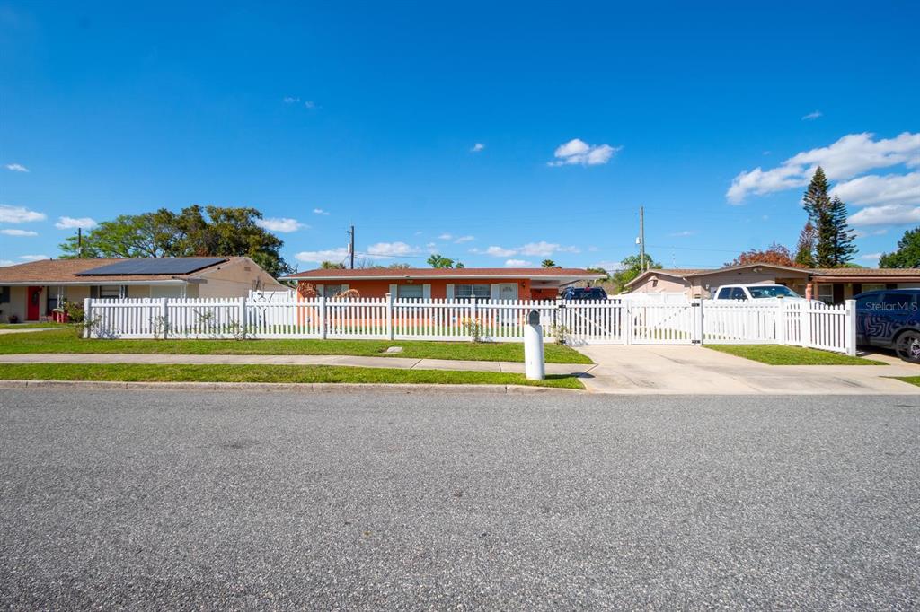A single-story orange house with a white picket fence and a driveway — 4401 EDGEBROOK, ORLANDO, FL